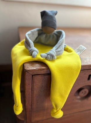 A yellow lovey sitting on the corner of a wooden table.